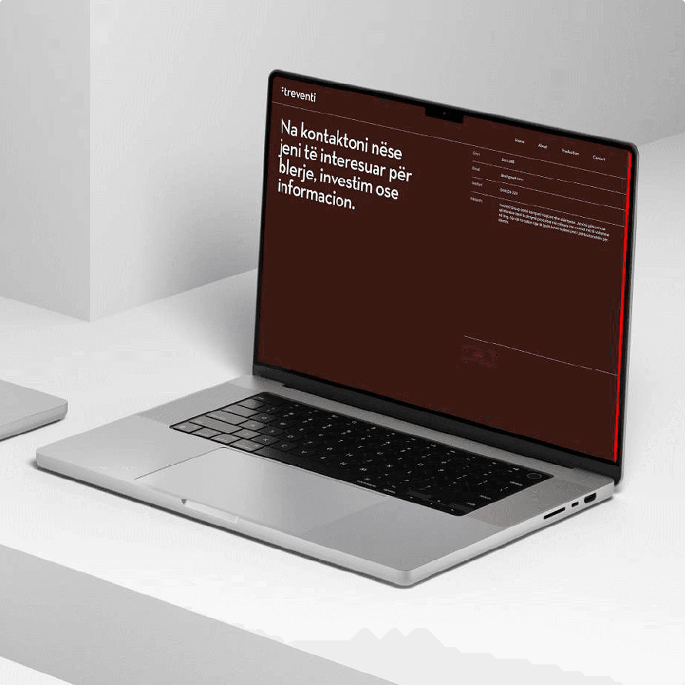 A laptop on a clean white desk displaying the Treventi website's contact section — Albanian copy set against the brand's signature red.